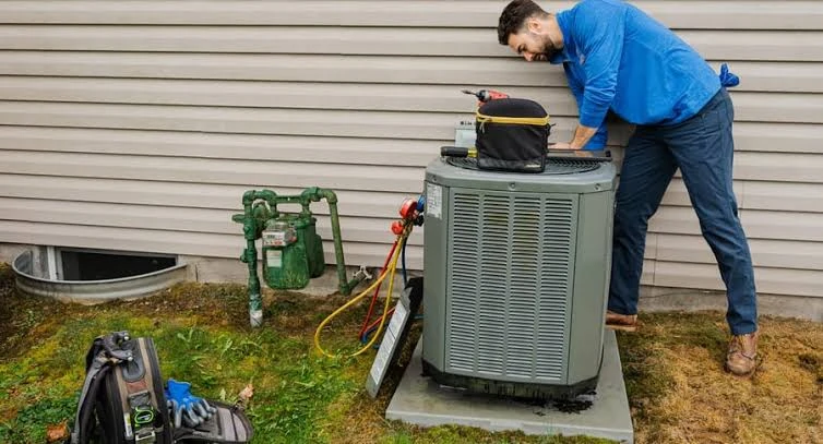 HVAC technician inspecting a residential outdoor air conditioning unit